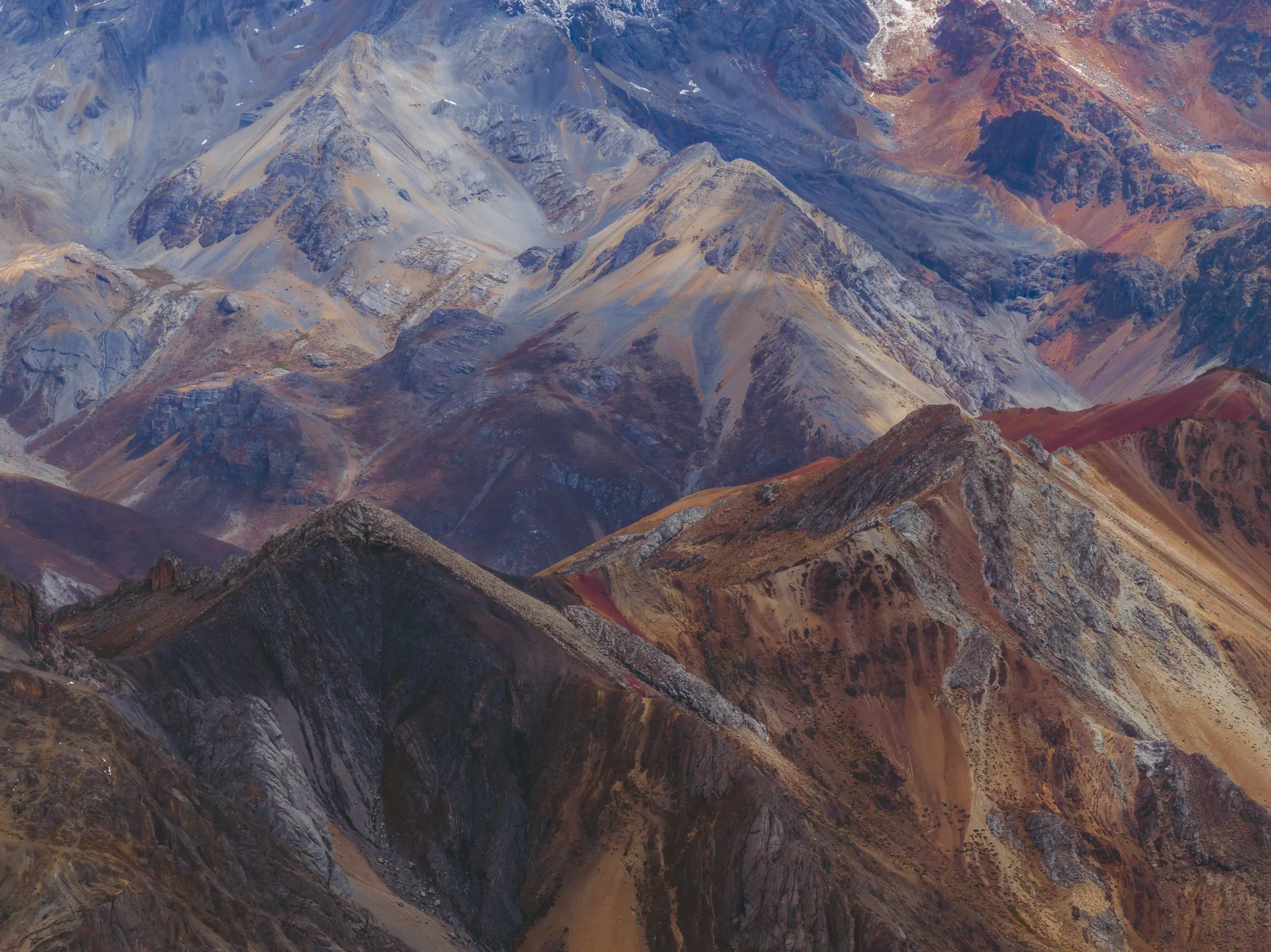 Folded mountain ridges in bands of rust red, violet, ochre and grey, Cordillera Huayhuash, Peru