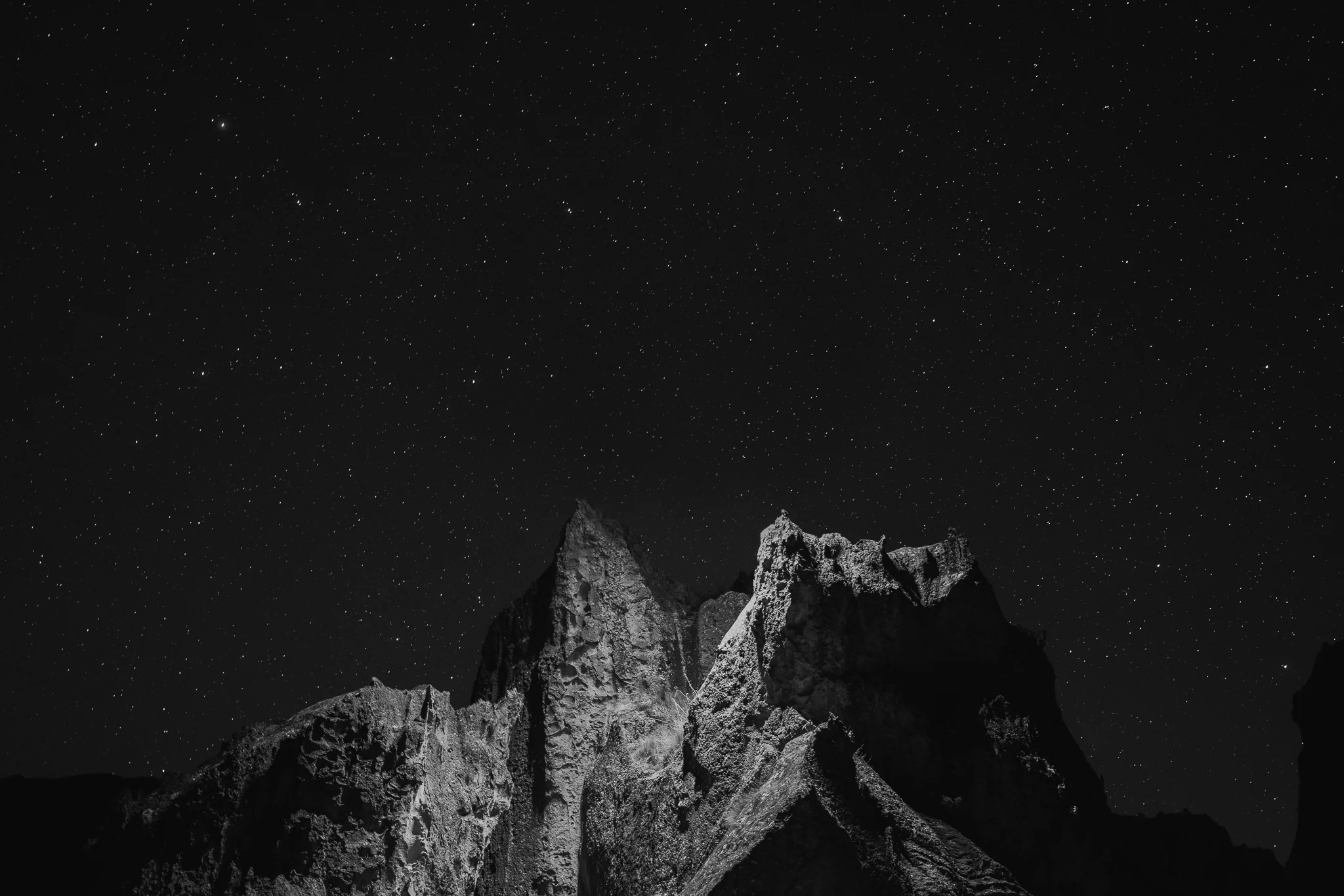 Black-and-white night photo of jagged rock towers silhouetted against a star-filled sky, Hatun Machay, Cordillera Negra, Peru
