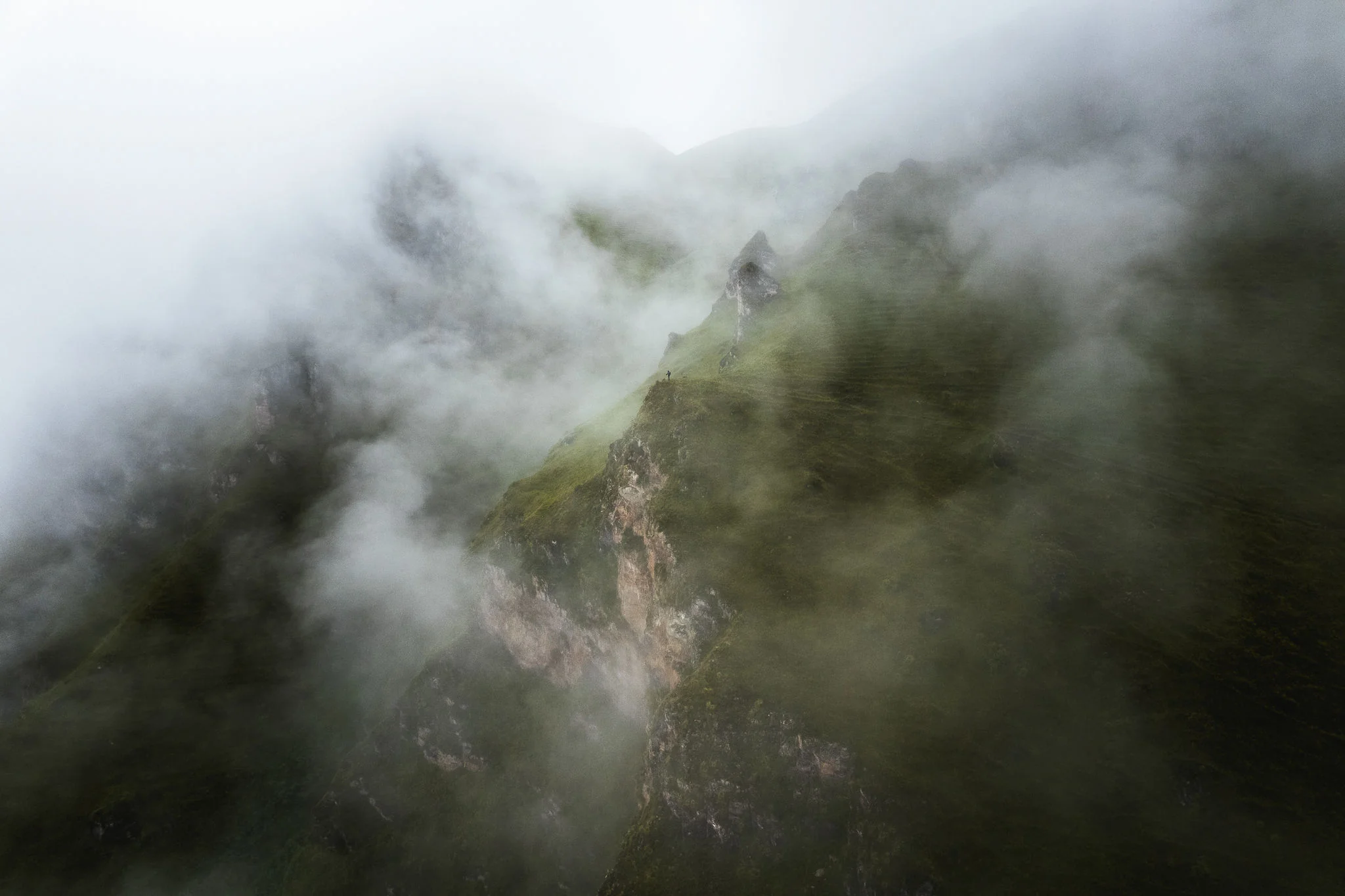 Cloud drifting across a steep green ridge and bands of rock, the slopes half hidden in mist, Ancascocha, Sacred Valley, Peru