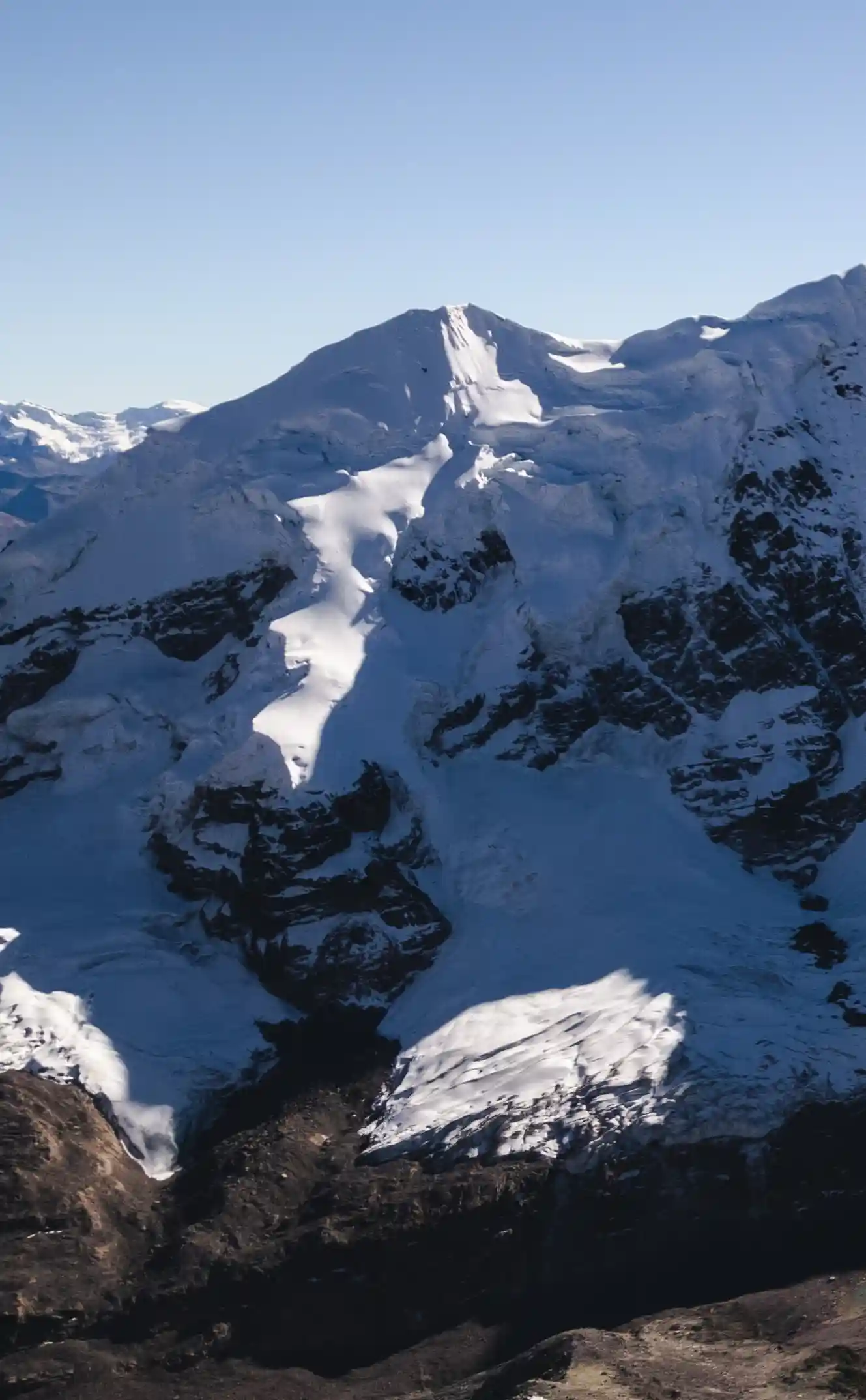 Una lengua de glaciar que baja desde la cumbre del Nevado Caracol hacia la roca oscura de abajo, región Cusco, Perú